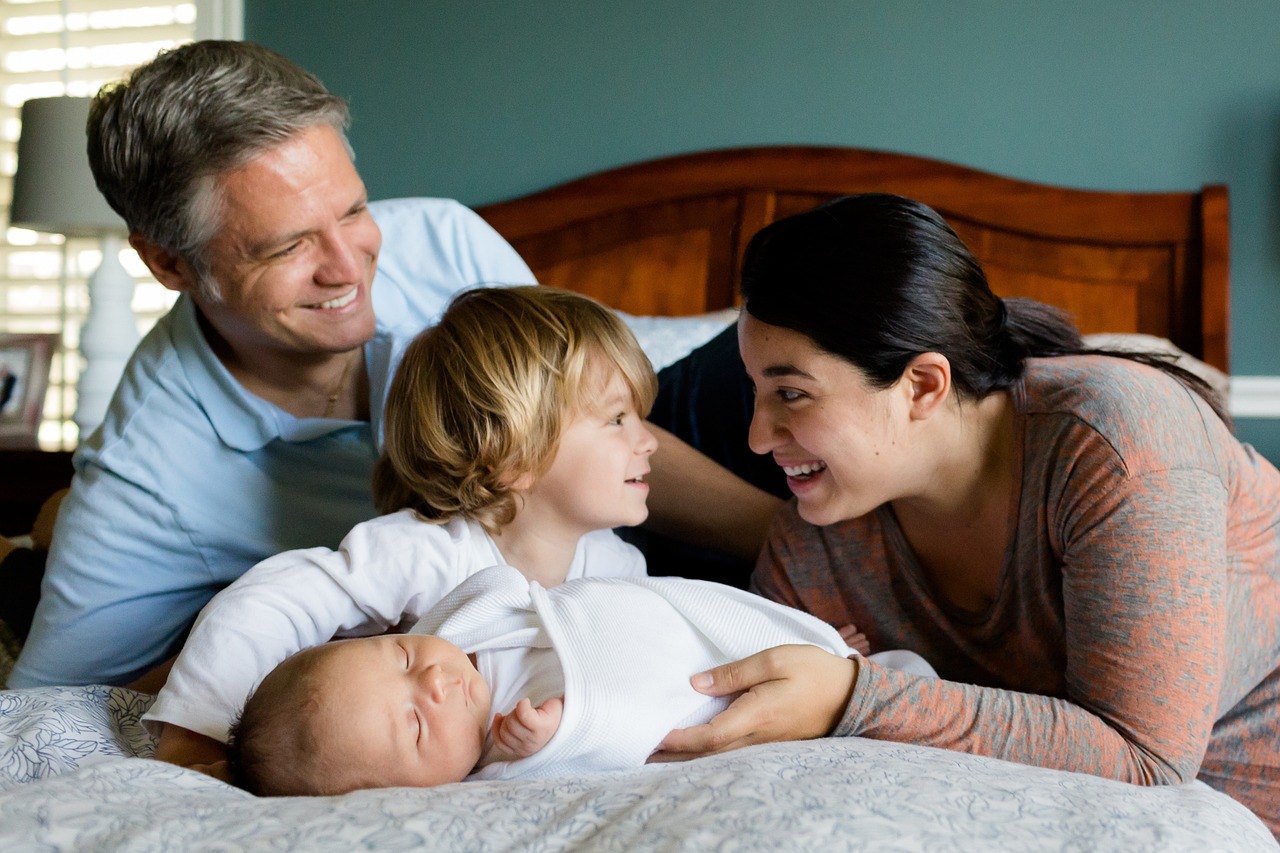 A family with parents and children together on a bed, emphasizing the importance of creating a Last Will and Testament to ensure the security and welfare of loved ones with Ostendorf Law.